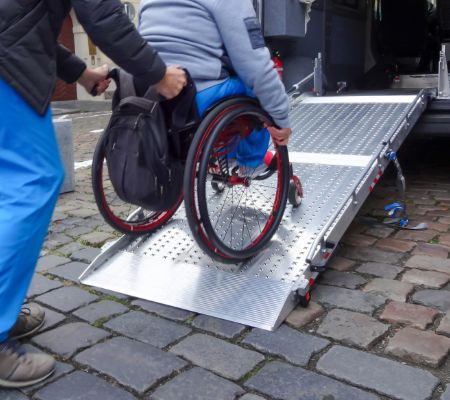 wózek inwalidzki wpychany na rampie do samochodu